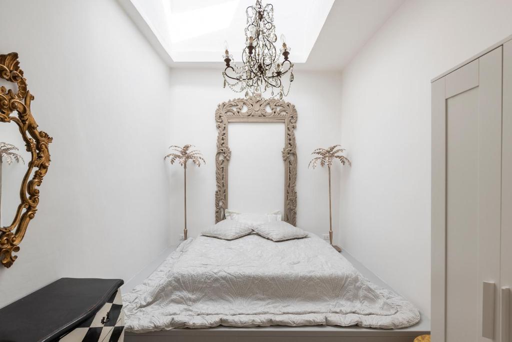 een witte slaapkamer met een bed en een kroonluchter bij SOGNO NEL RINASCIMENTO in Florence