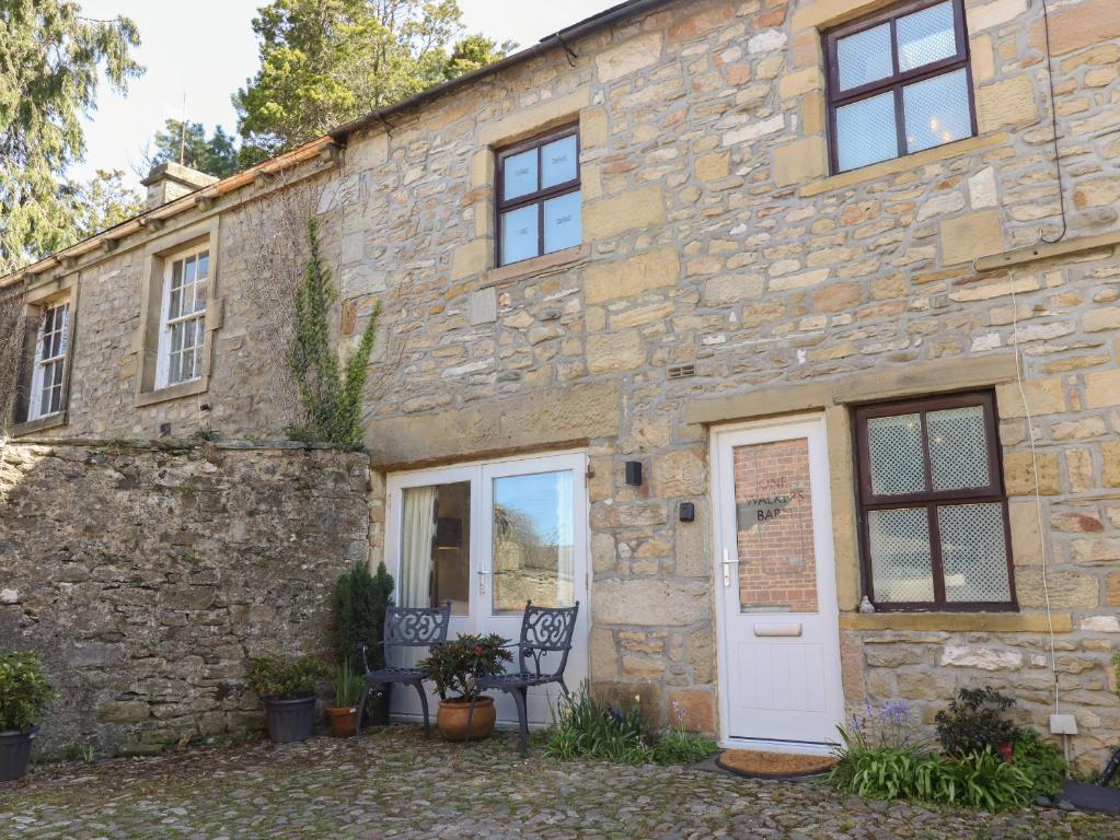 een stenen huis met een witte deur en ramen bij 1 Walkers Barn in Settle