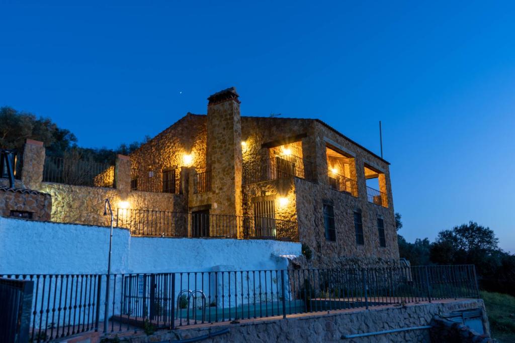 un viejo edificio de piedra con luces encendidas por la noche en Casas Rurales Las Cuevas El Rincón, en Fuentes de León