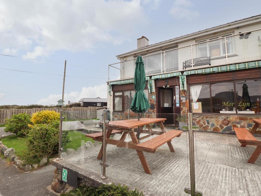 a picnic table with an umbrella in front of a building at Morlyn Guest House Apartment in Harlech