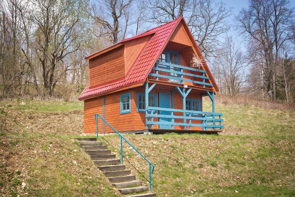 una pequeña casa con techo rojo en un campo en Domek przy stoku en Lądek-Zdrój