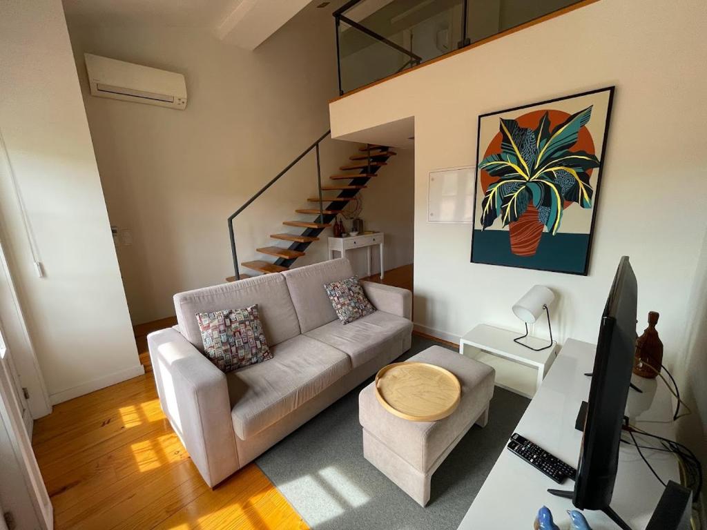 a living room with a couch and a staircase at Mezzanine Apartment in Guimarães