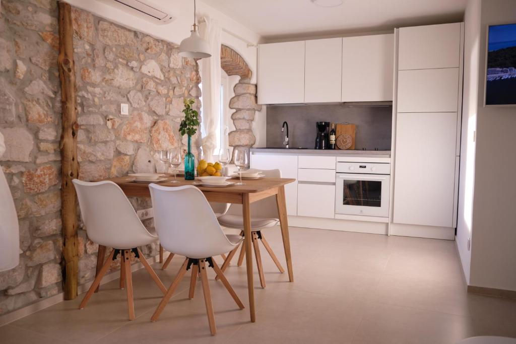 una cucina con tavolo in legno e sedie bianche di Apartment House Bucul a Mali Lošinj (Lussinpiccolo)