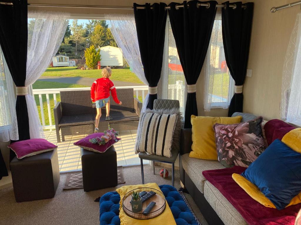 una niñita parada en una sala de estar mirando por la ventana en Prestige caravan,Seton Sands holiday village, WiFi, en Port Seton