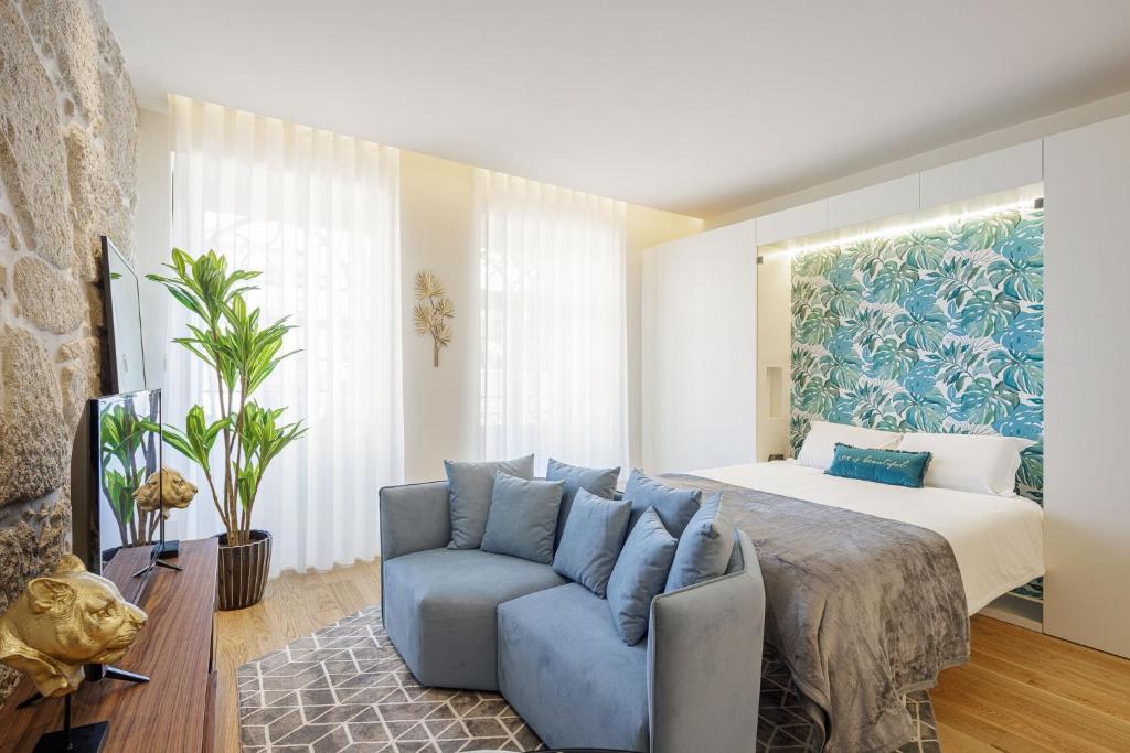 een slaapkamer met een bed en een blauwe bank bij The Downtown Charming Apartments in Porto