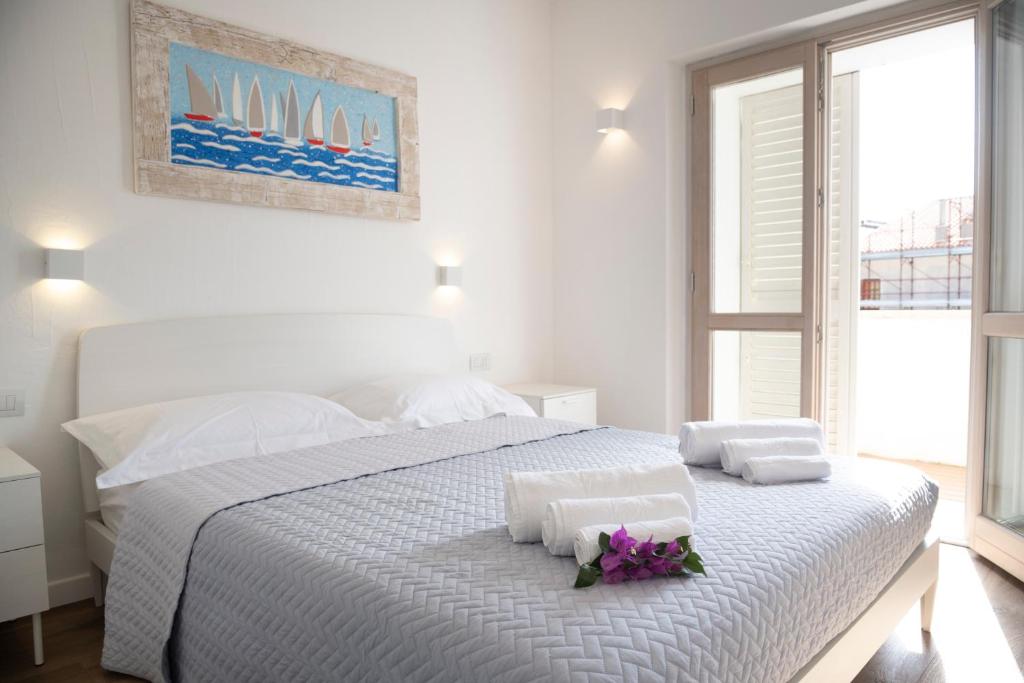 a white bedroom with a white bed with flowers on it at Sardinia Gold Luxury Apartment in Palau