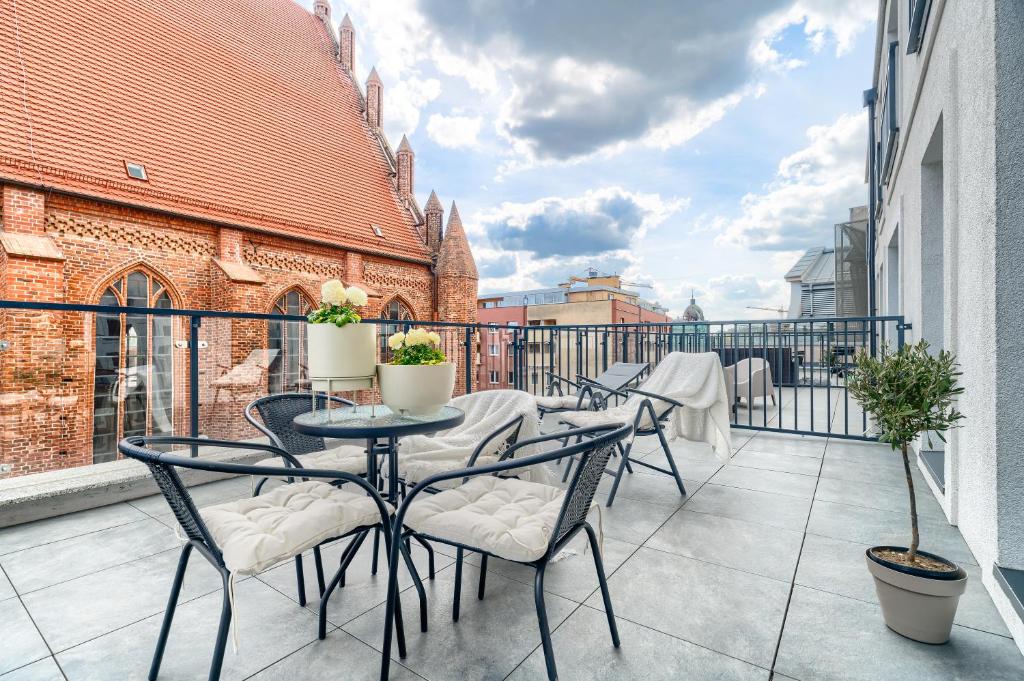 einen Balkon mit Tischen und Stühlen auf einem Gebäude in der Unterkunft Apartament 1000 Stare Miasto Apartamenty No.1 in Stettin