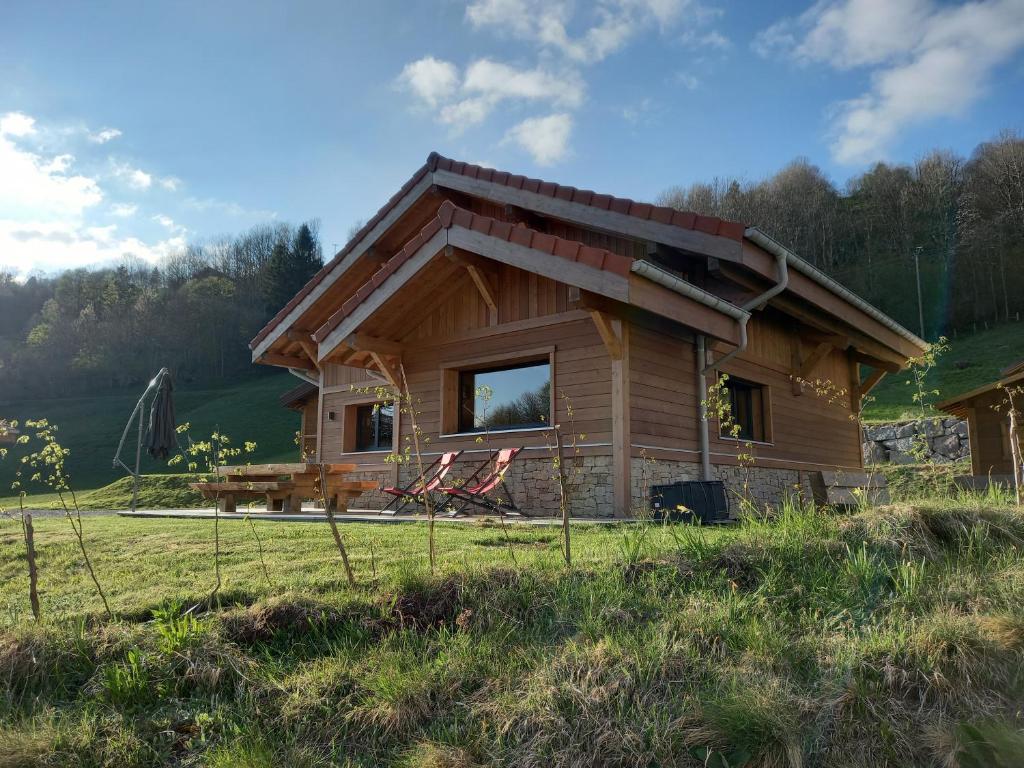 eine Blockhütte mit einem großen Fenster auf einem Feld in der Unterkunft TOUT NEUF - Chalet Paul avec sauna in La Bresse