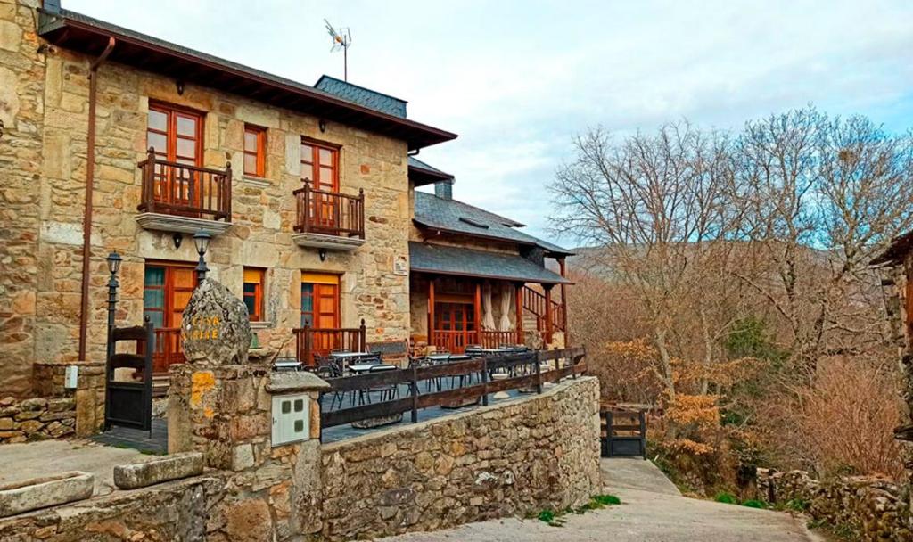 ein altes Steinhaus mit einer Steinmauer in der Unterkunft La Casa de Irene in Lubián