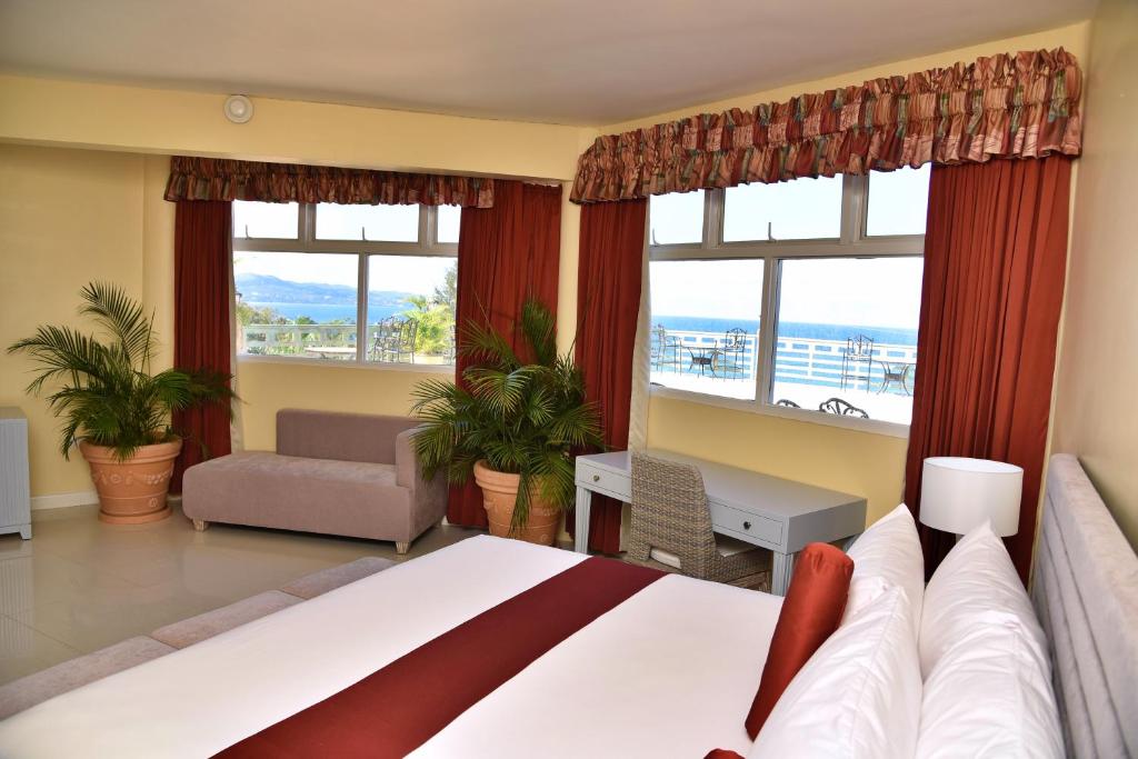 a bedroom with a large bed with a view of the ocean at Hotel Grand A View in Montego Bay