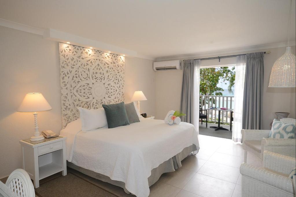 a bedroom with a white bed and a balcony at Sugar Bay Barbados - All Inclusive in Bridgetown