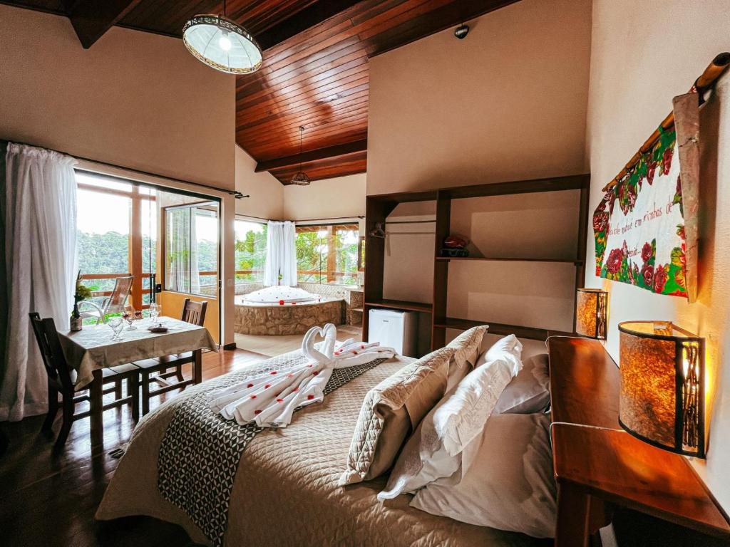 a bedroom with a large bed and a dining room at Pousada Toca da Onça in Gonçalves