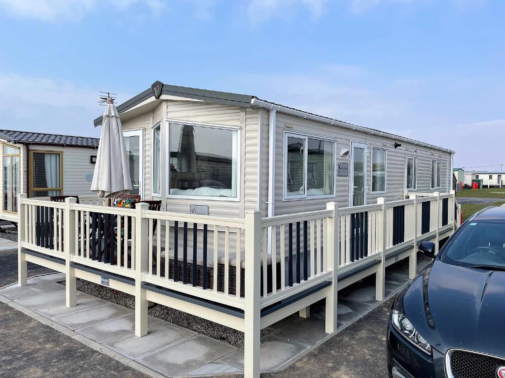 a mobile home with a porch and an umbrella at bracken lodge in Chapel Saint Leonards