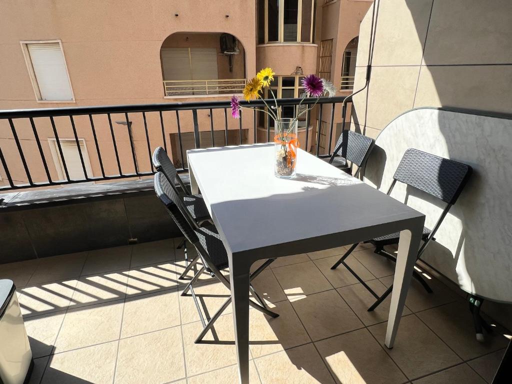 stół i krzesła na balkonie z wazonem kwiatów w obiekcie APARTAMENTO LA MATA w mieście La Mata