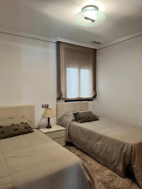 sypialnia z dwoma łóżkami i oknem w obiekcie APARTAMENTO LA MATA w mieście La Mata