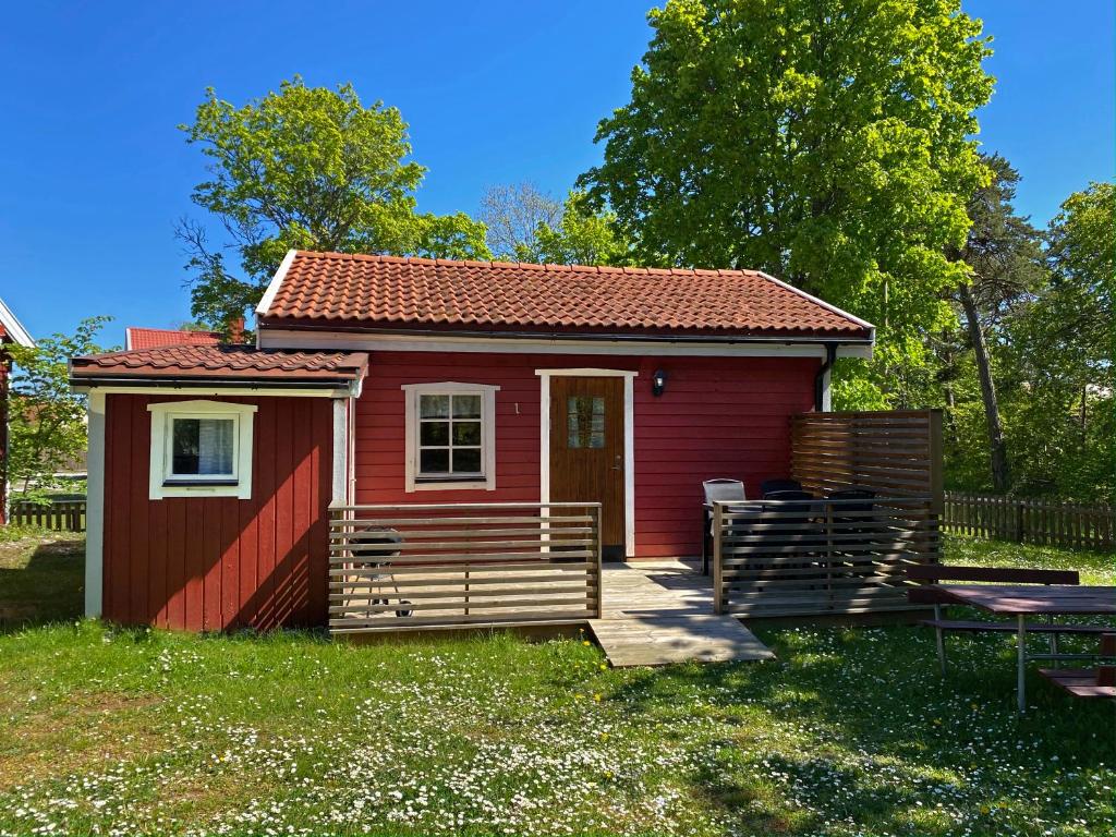 ein rotes winziges Haus mit einer Veranda und einem Tisch in der Unterkunft Brissundsbyn in Visby