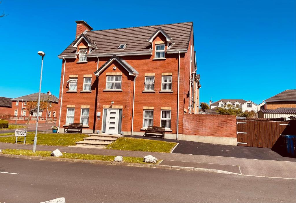 een groot rood bakstenen huis met een witte deur bij The Grange, Portrush Sleeps 13 6 bedrooms in Portrush