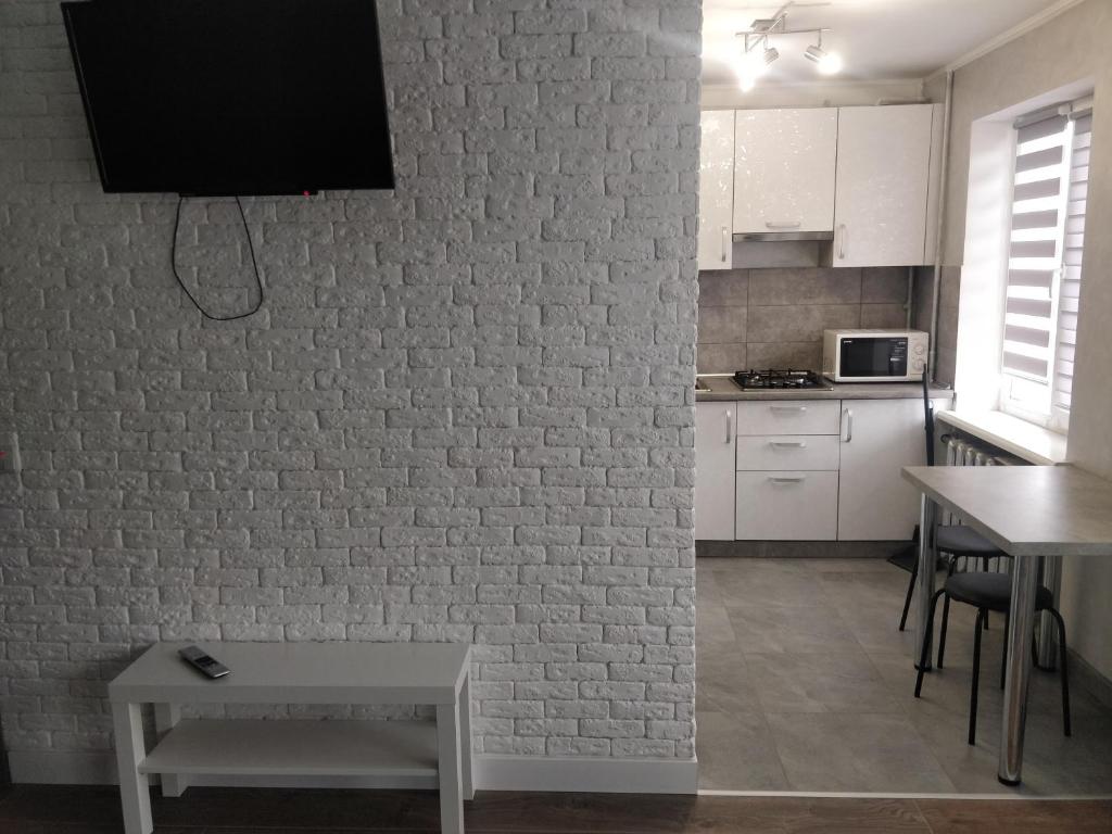 una cocina con una pared de ladrillo blanco y una mesa en Studio COMFORT on Golovna street, en Chernivtsi