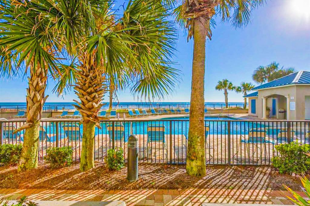 a resort with a pool and palm trees and the ocean at Bluewater in Orange Beach