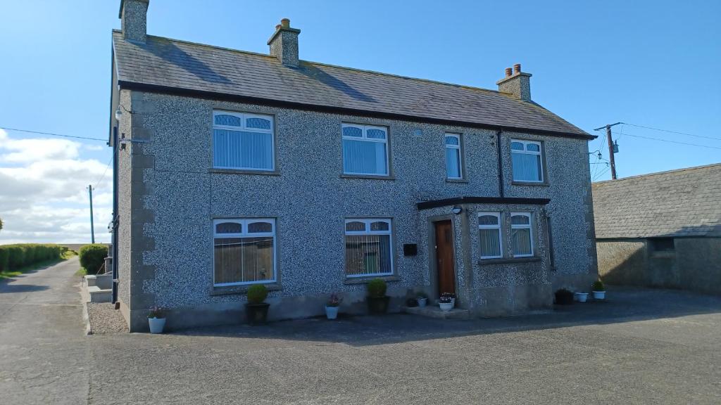 a blue brick house with white windows on a street at Causeway Coast Carrivcashel Holiday Home in Ballymoney