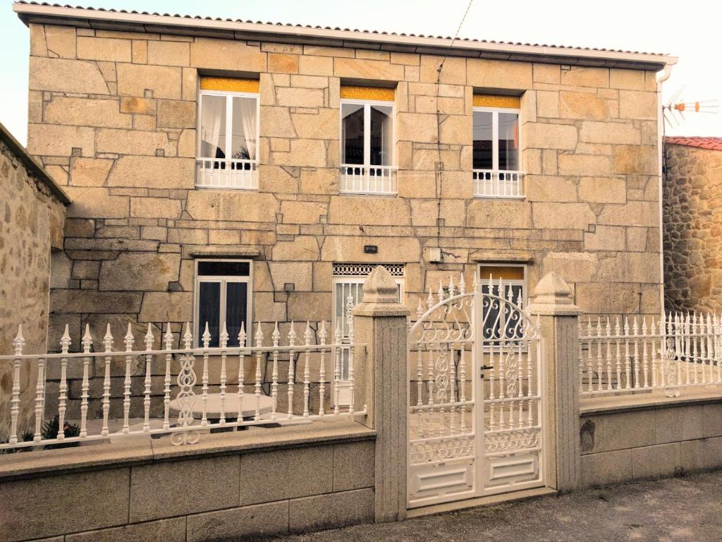 een stenen huis met een wit hek ervoor bij Casa Rua in Lira