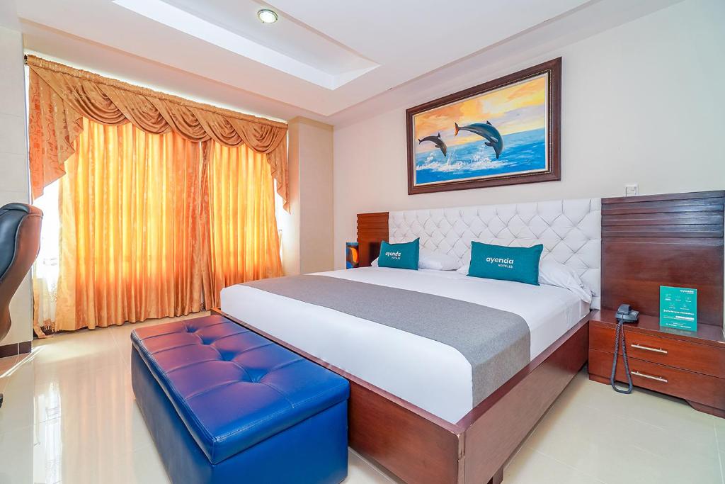 a bedroom with a large bed with a blue stool at Ayenda Yubarta in Buenaventura