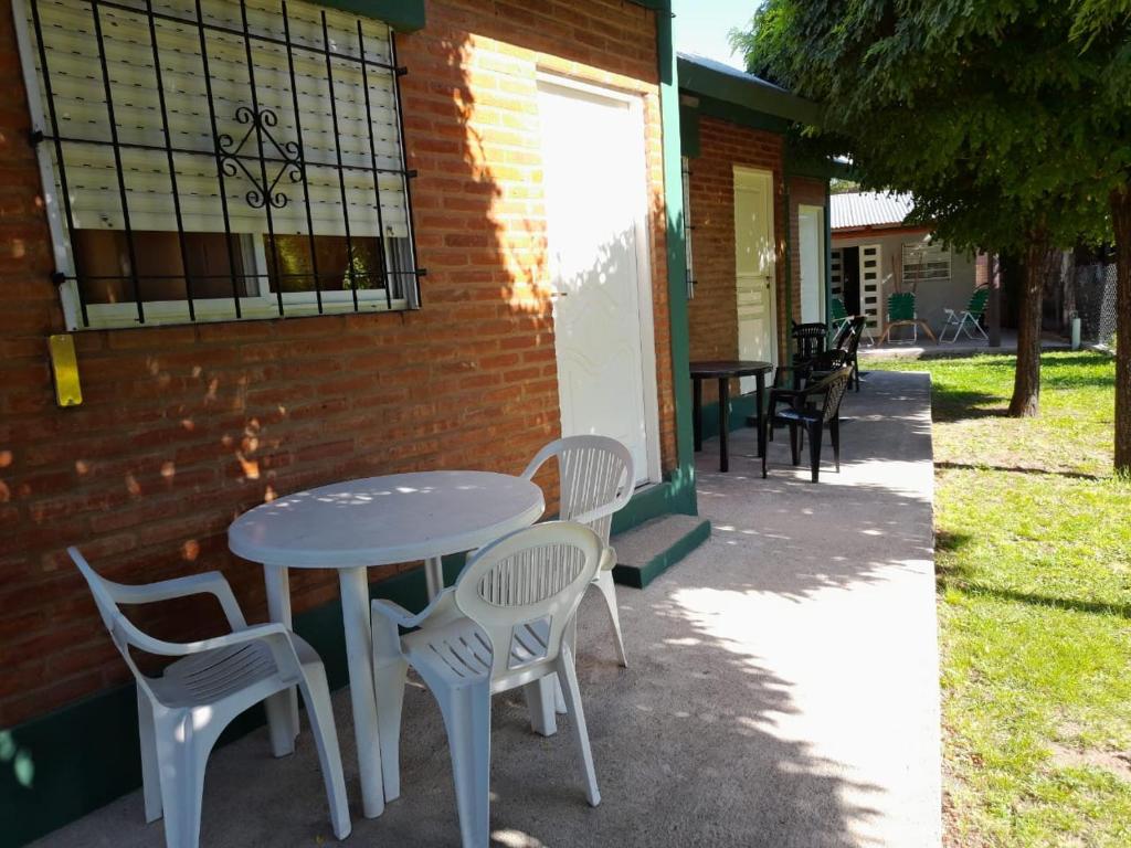 Biały stół i krzesła obok ceglanego budynku w obiekcie Cabañas Soleado Villa Cura Brochero w mieście Villa Cura Brochero