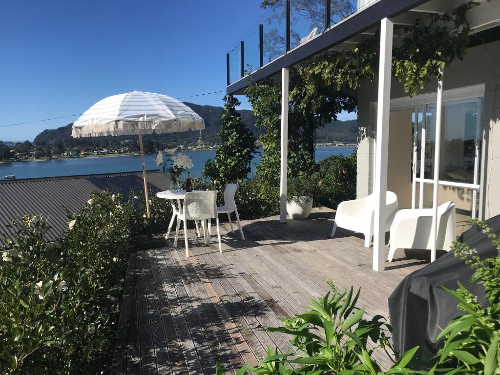 eine Terrasse mit einem Tisch, Stühlen und einem Sonnenschirm in der Unterkunft Serendipity Adorable Tairua Studio in Tairua