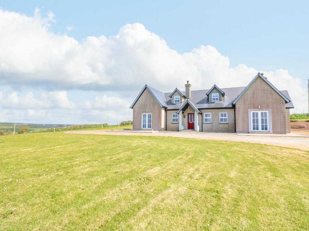 a house with a large grass field in front of it at Josie's House in Fethard on Sea