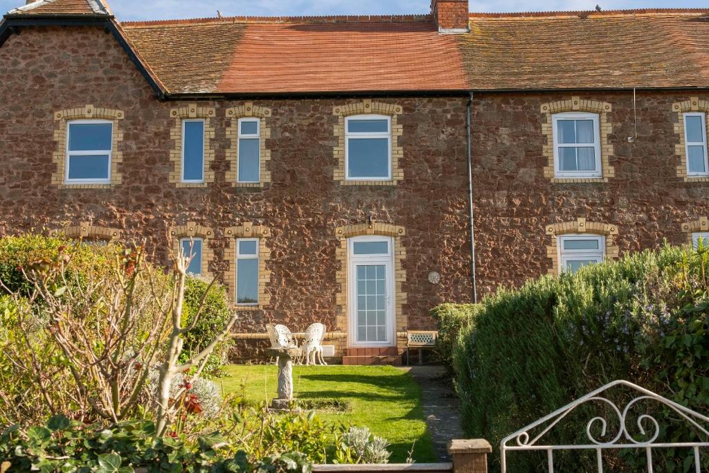 an old brick house with a garden in front of it at Harbour View Cottage in Watchet