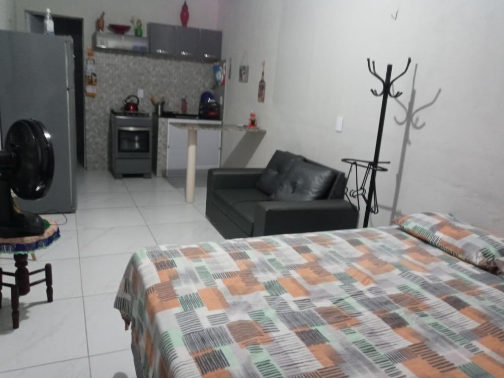 a bedroom with a bed and a couch and a kitchen at Kitnet mobiliado, confortável e bem localizado. in Fortaleza