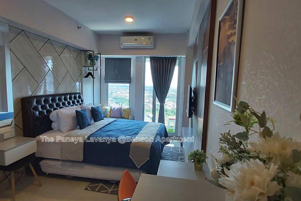 a bedroom with a bed with a blue blanket and a window at The Paneya Lavanya @Benson Apartment in Surabaya