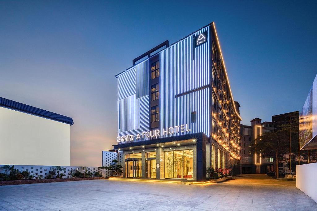 a hotel with a building with lights on it at Atour Hotel Haikou East High-Speed Railway Station Xueyuan Road in Pin-lien
