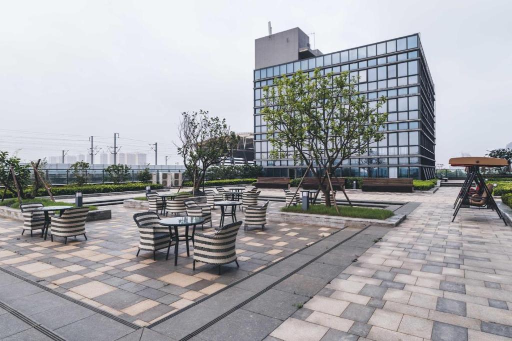 dziedziniec ze stołami i krzesłami oraz budynek w obiekcie Atour Hotel Suzhou North High-Speed Railway Station w mieście Suzhou