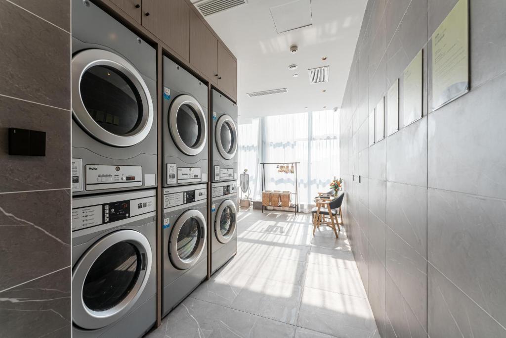 a laundry room with four washer and dryer machines at Atour Hotel Yiwu International Trade Transportation Center in Yiwu