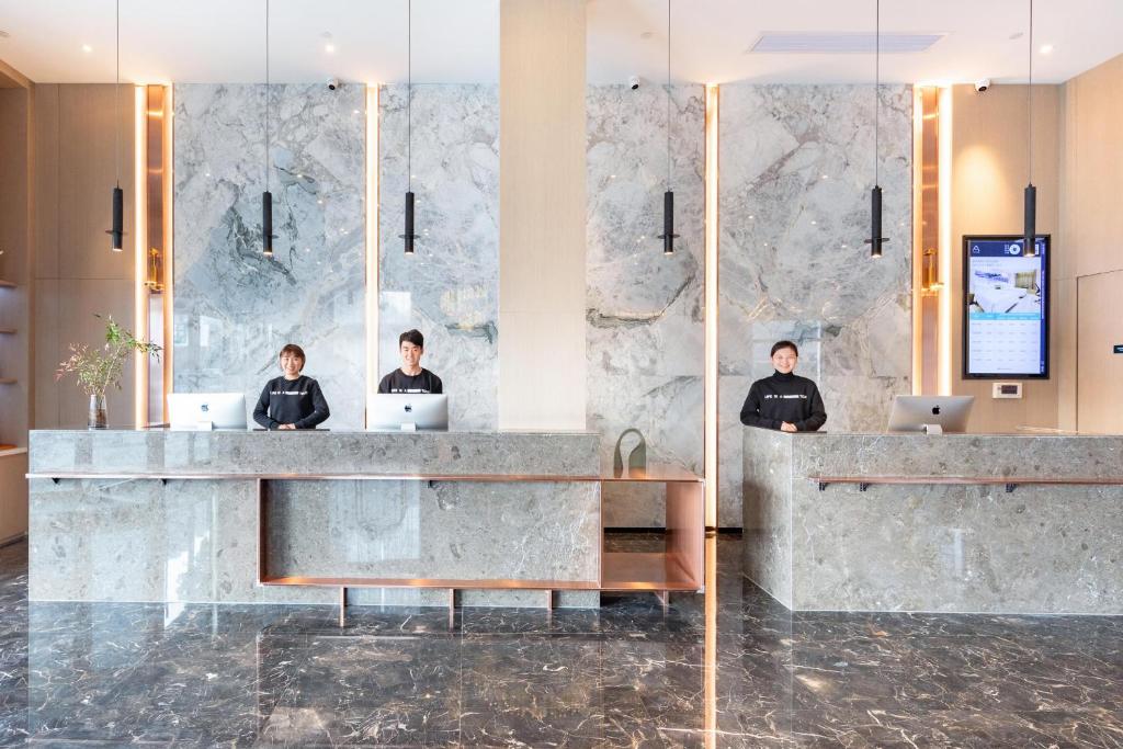 a lobby with three people sitting at a counter with their laptops at Atour Hotel Anqing Wuyue Plaza in Anqing