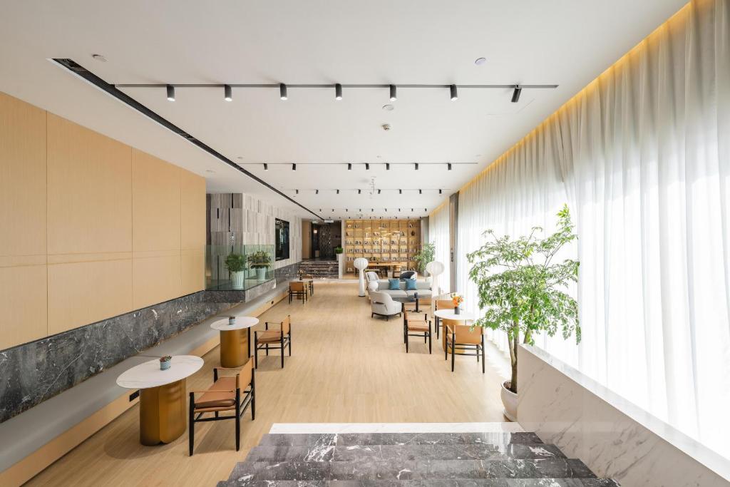 a lobby with tables and chairs and a living room at Atour Hotel Chongqing West Station in Chongqing