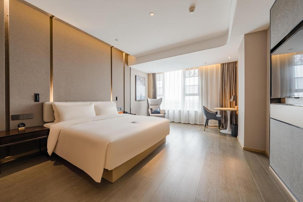 a hotel room with a large bed and a kitchen at Atour Hotel Jiaxing Pinghu in Pinghu