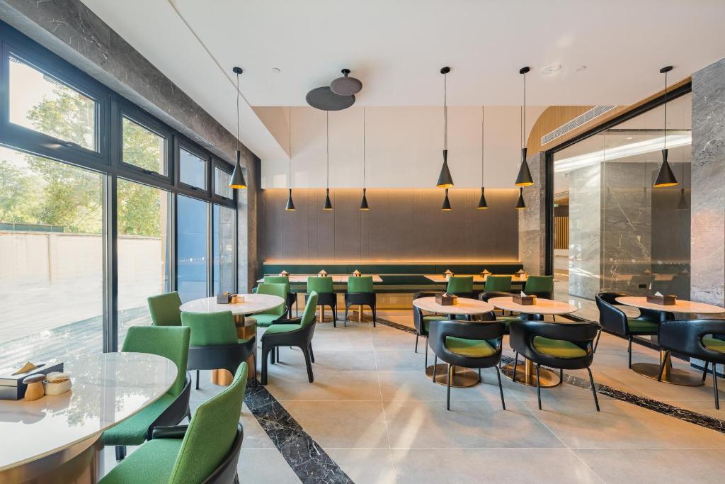ein Esszimmer mit Tischen und grünen Stühlen in der Unterkunft Atour Hotel Shijiazhuang South Construction Street in Shijiazhuang