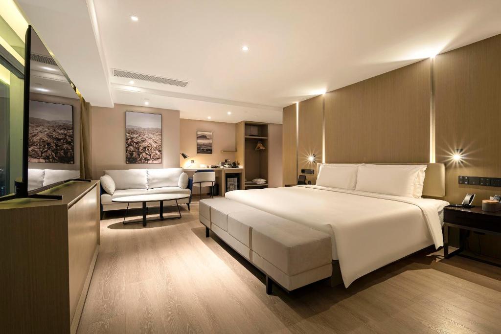 a bedroom with a large bed and a living room at Atour Hotel Wuhan Hankou Financial Center in Wuhan