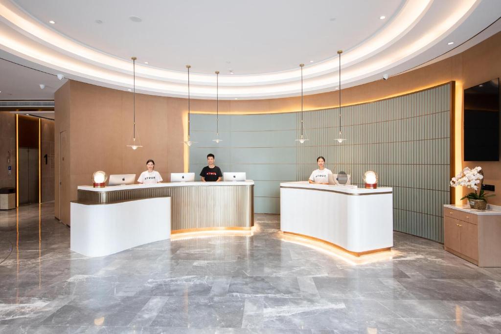 a lobby of a hotel with three people sitting at desks at Atour Hotel Wuhan International Expo Center in Wuhan