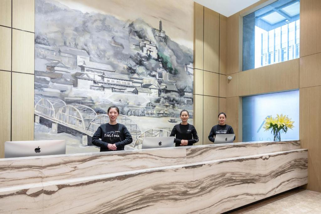 a group of three people sitting at a reception desk at Atour Hotel Lanzhou Xiguan Zhengning Road in Lanzhou