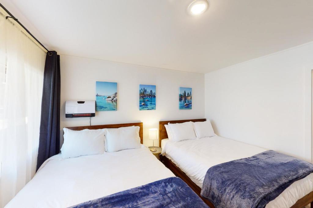 2 camas en una habitación con sábanas blancas y mantas azules en The Chalet at Kings Beach, en Kings Beach