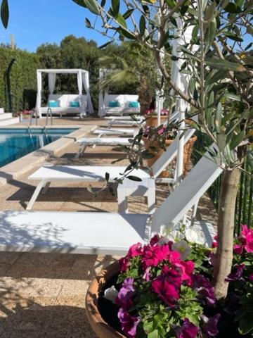 a row of chairs and flowers next to a pool at The Desmais in Cala Galdana