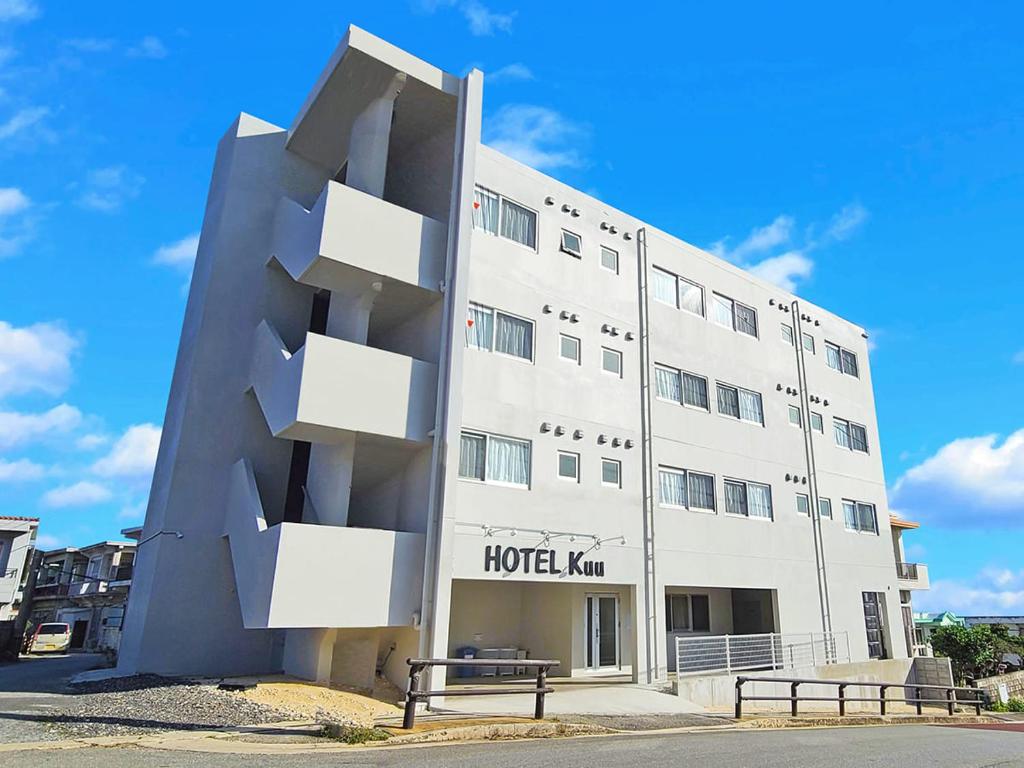 un gran edificio blanco con dos bancos delante en HOTEL Kuu, en Isla Miyako