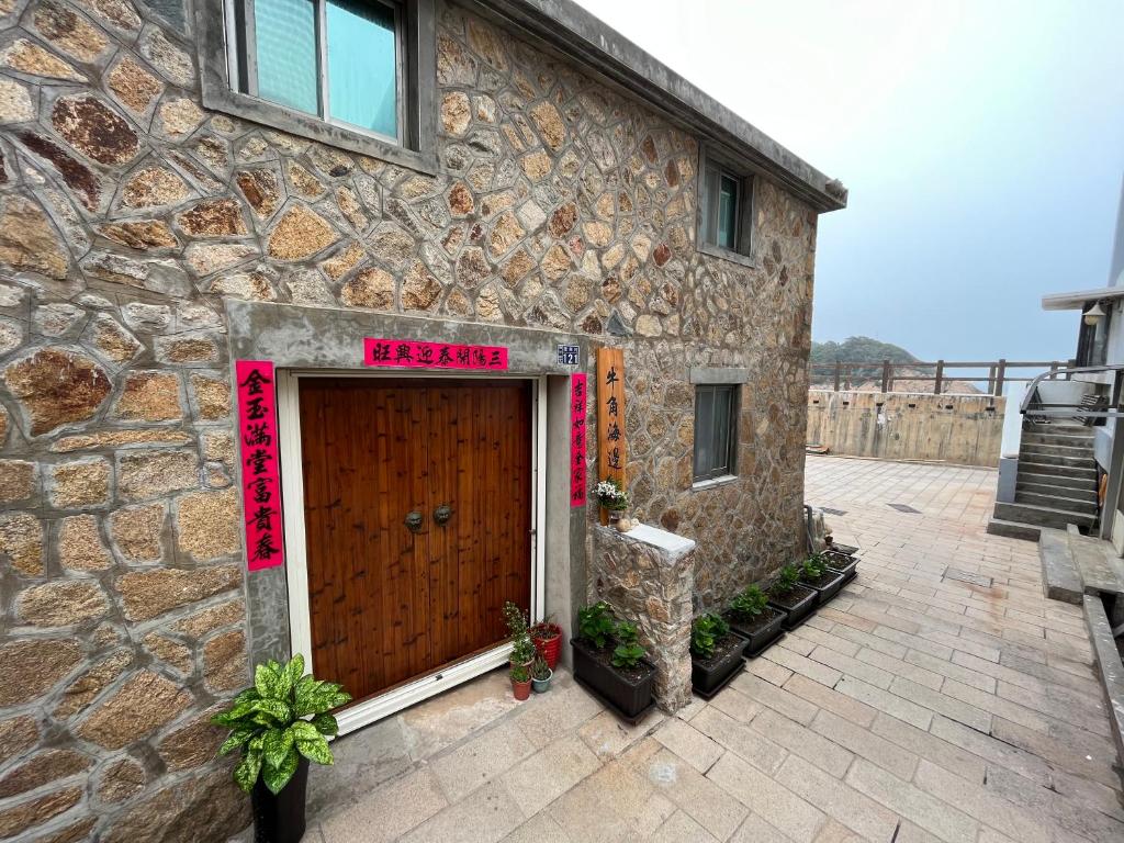 a stone building with a brown door with a sign on it at Horn Seaside Homestay in Nangan