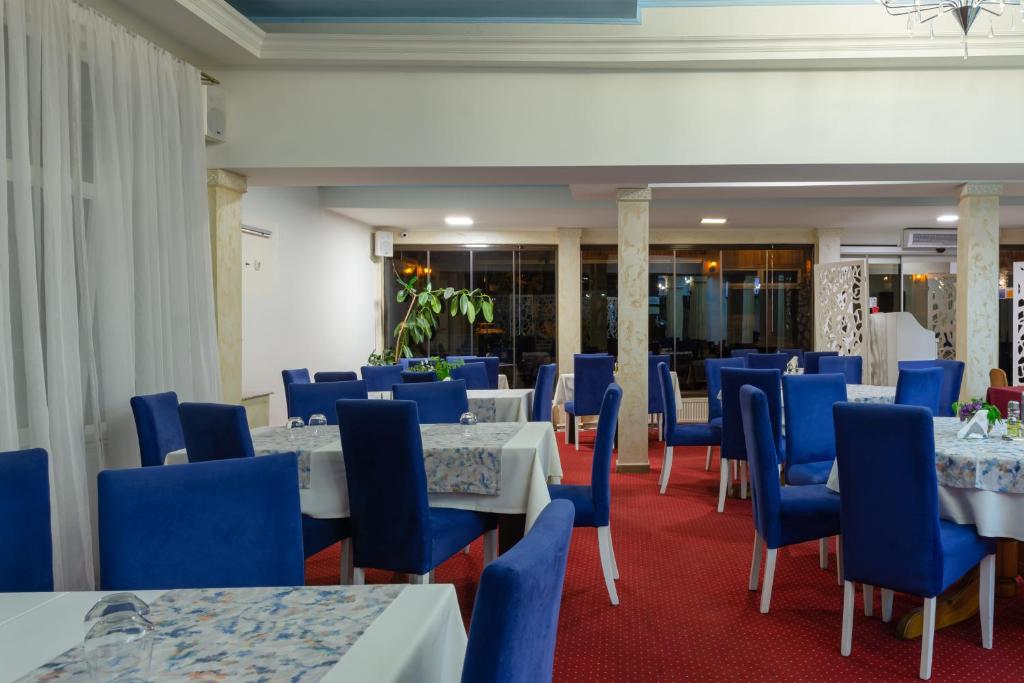 a dining room with tables and blue chairs at Hotel Grand in Eforie Nord