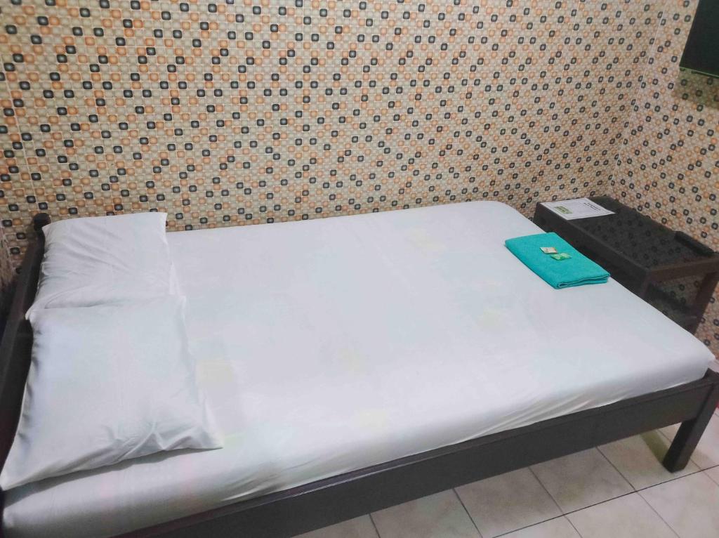 a small bed with a blue folder on top of it at Bayu Murti Inn Kaliurang Yogyakarta RedPartner in Kaliurang