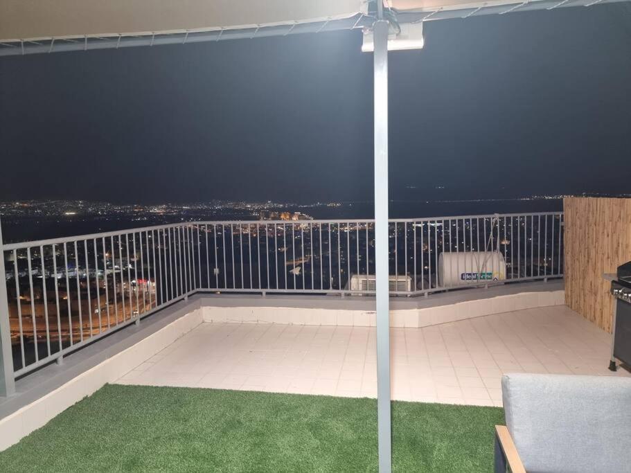 een balkon met uitzicht op de stad in de nacht bij דירת זוּגַג מפנקת עם מרפסת משגעת ונוף למפרץ. in Eilat