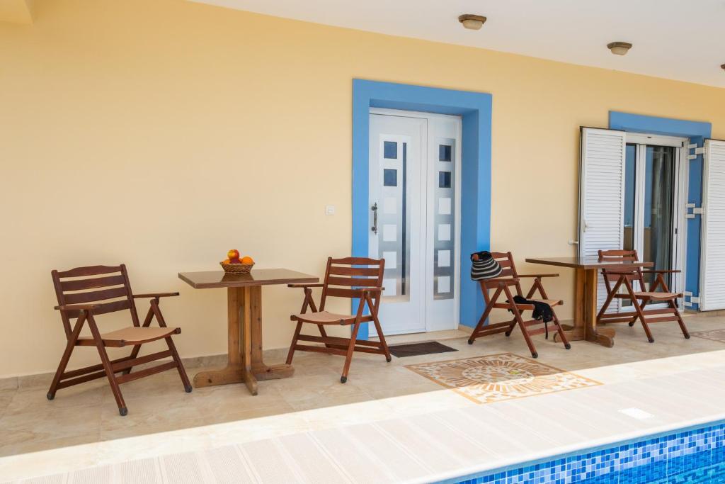 a room with chairs and a table and a pool at Karpathos View Villa in Karpathos